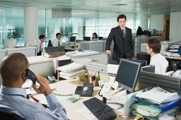 Employees working in an open office setting, talking to their manager about unpaid wages.